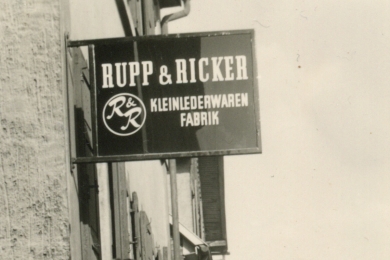 <h5>1962</h5><p>Firmenschild der Firma Rupp & Ricker in der Ludwigstrasse. Später wird die Marke Esquire auch Firmenname.																																																																																																																																																																										</p>